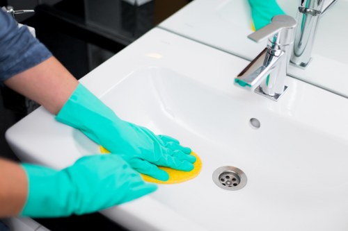 Local Hammersmith cleaner dusting shelves in a residential apartment