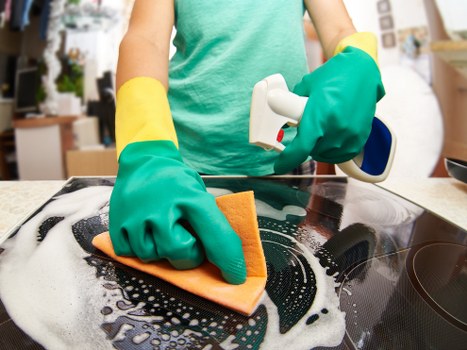 Professional cleaner tidying a kitchen in Hammersmith